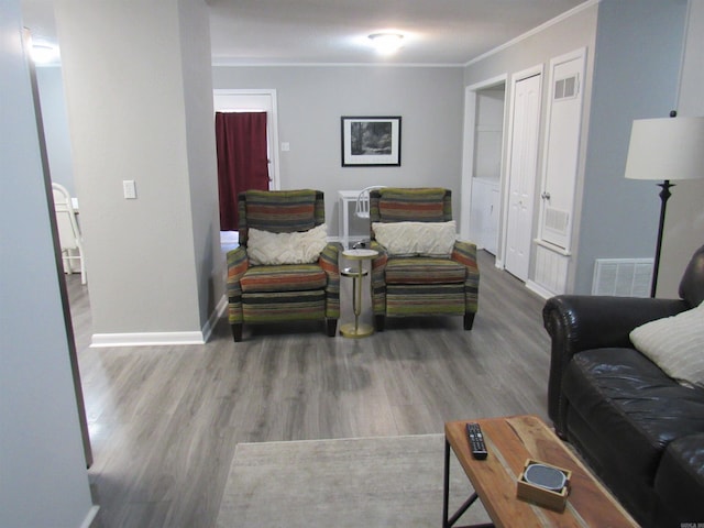 living area featuring baseboards, visible vents, crown molding, and wood finished floors