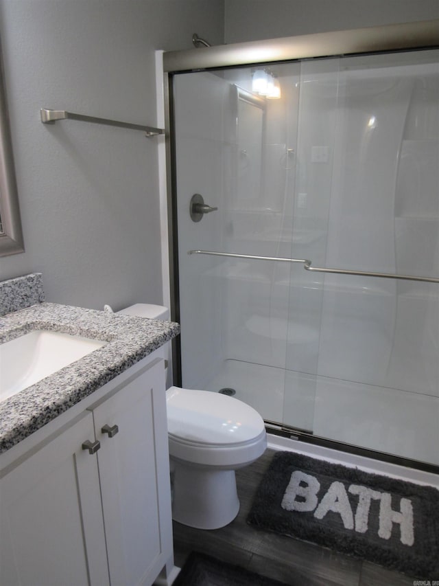 full bath with toilet, wood finished floors, a shower stall, and vanity