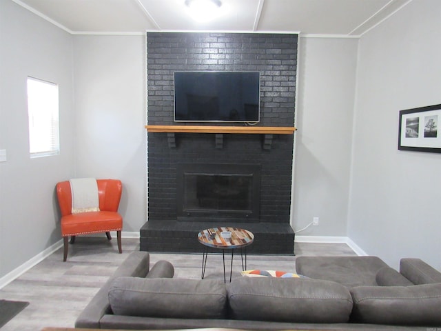 living room with ornamental molding, a brick fireplace, wood finished floors, and baseboards