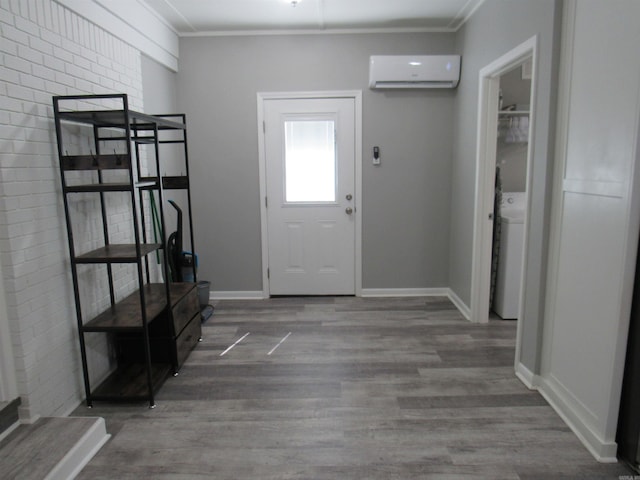 entrance foyer with ornamental molding, a wall unit AC, wood finished floors, and baseboards