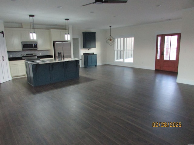 kitchen with stainless steel appliances, a ceiling fan, white cabinets, open floor plan, and tasteful backsplash