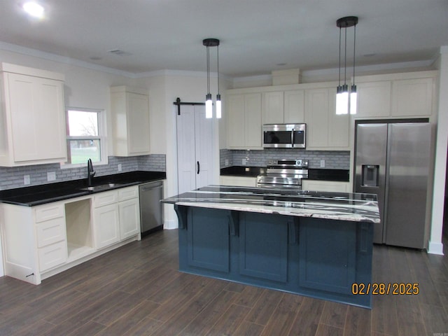 kitchen featuring stainless steel appliances, a barn door, a sink, and white cabinets