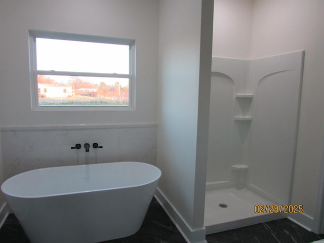 bathroom featuring a soaking tub, a shower, and wainscoting