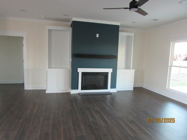 unfurnished living room with ornamental molding, dark wood-style flooring, a glass covered fireplace, and baseboards