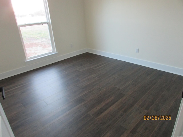 unfurnished room with baseboards and dark wood-type flooring