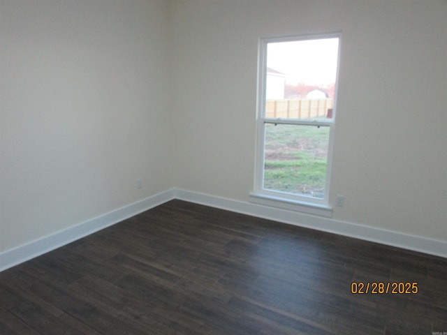 spare room featuring dark wood-style flooring and baseboards