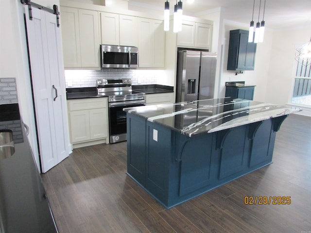 kitchen with tasteful backsplash, appliances with stainless steel finishes, dark wood finished floors, and a barn door