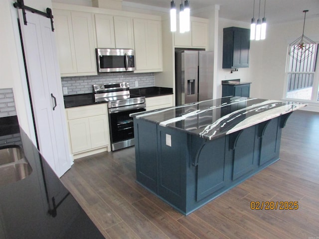 kitchen featuring appliances with stainless steel finishes, dark countertops, dark wood finished floors, and a barn door