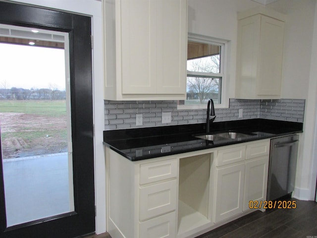 kitchen featuring a sink, white cabinetry, stainless steel dishwasher, tasteful backsplash, and dark countertops