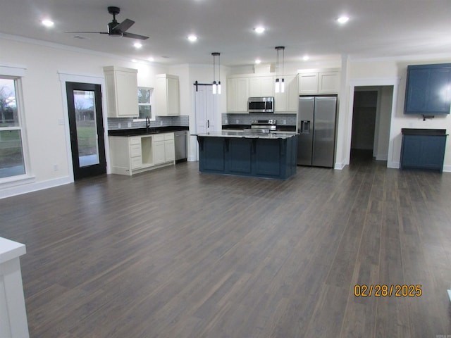 kitchen with open floor plan, ceiling fan, appliances with stainless steel finishes, and dark countertops