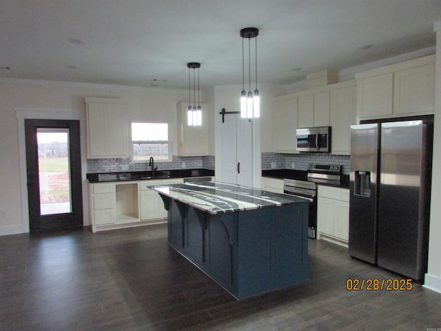 kitchen with dark countertops, backsplash, appliances with stainless steel finishes, white cabinets, and a sink