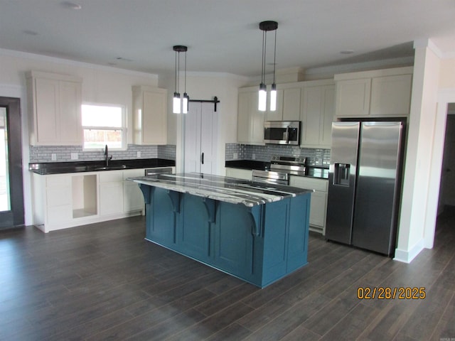 kitchen with a barn door, appliances with stainless steel finishes, white cabinets, and a center island