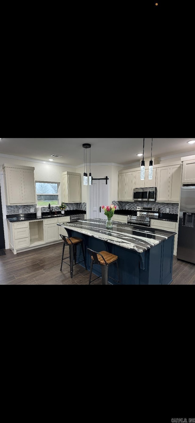 kitchen featuring stainless steel appliances, white cabinetry, decorative backsplash, and a kitchen breakfast bar