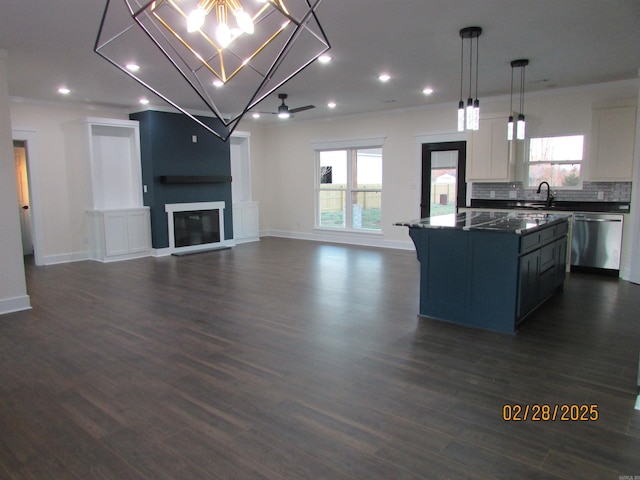 kitchen with a kitchen island, stainless steel dishwasher, tasteful backsplash, dark countertops, and a glass covered fireplace