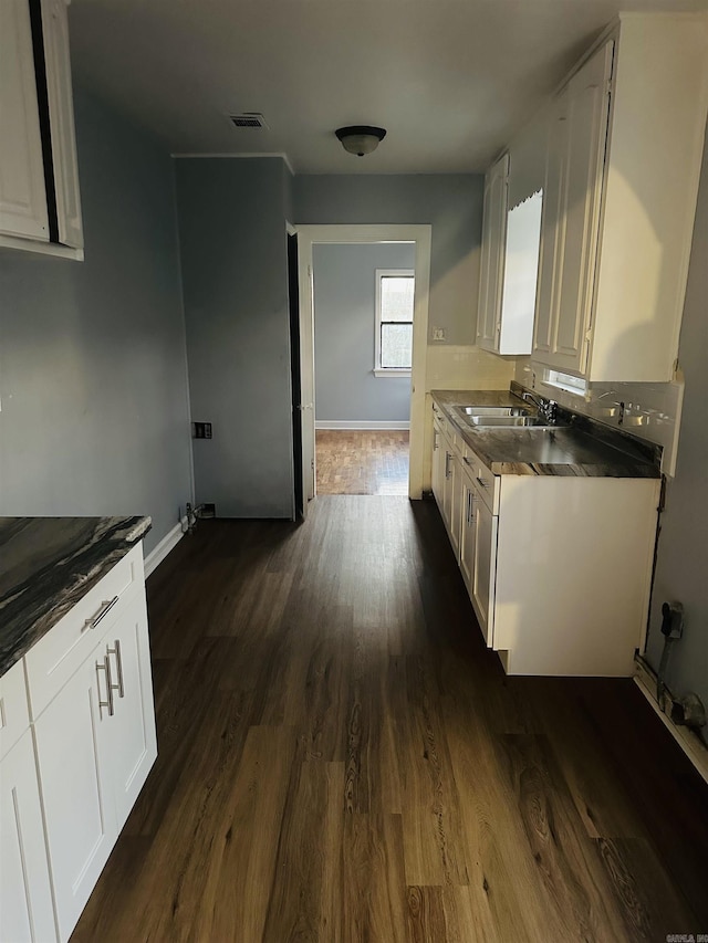 kitchen with visible vents, white cabinets, and a sink