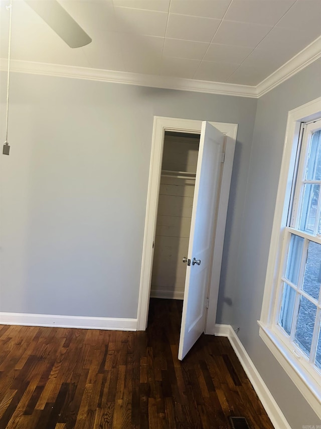 unfurnished bedroom with dark wood-type flooring, crown molding, and baseboards