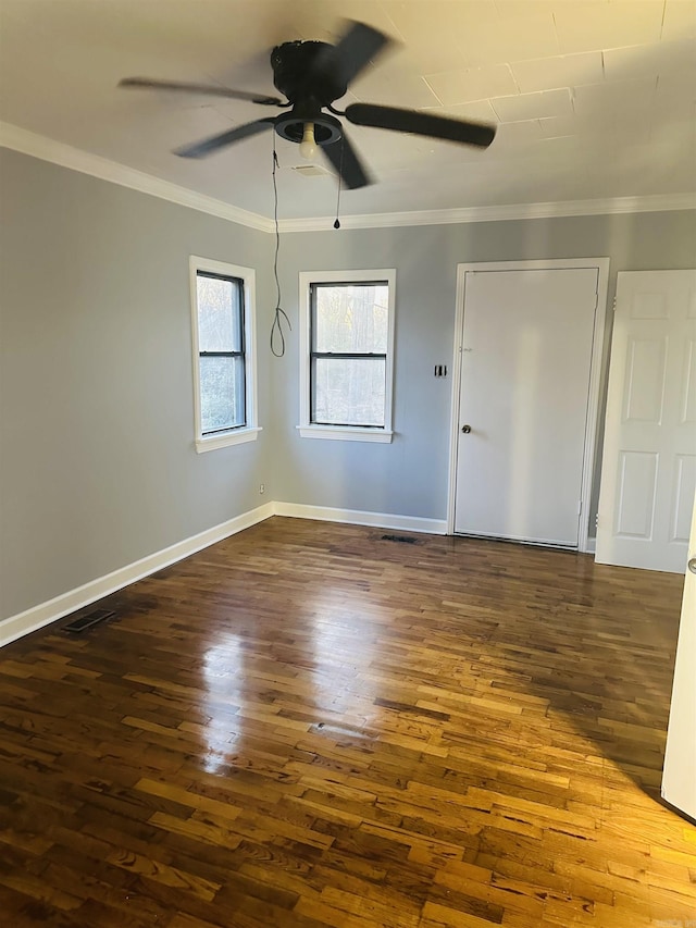 spare room featuring visible vents, baseboards, dark wood finished floors, ceiling fan, and crown molding