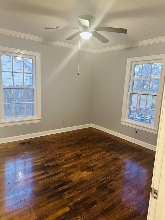 empty room with dark wood-style floors, ornamental molding, visible vents, and baseboards