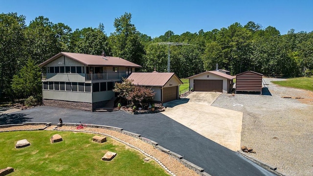 view of front facade featuring an outbuilding, a front yard, a sunroom, a garage, and stairs