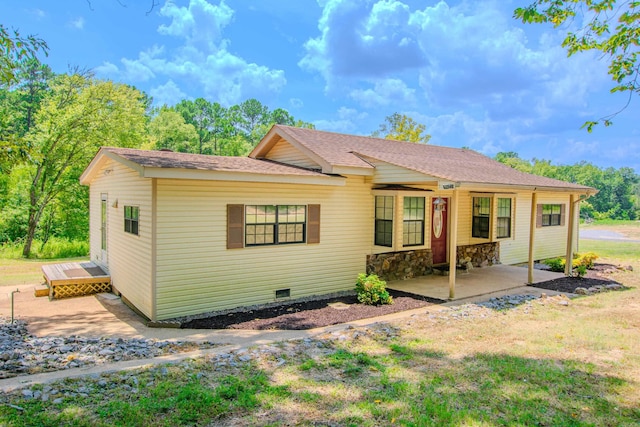 view of front of property with a patio, a shingled roof, stone siding, crawl space, and a front yard