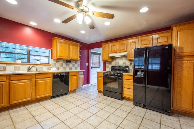 kitchen with light countertops, a sink, under cabinet range hood, and black appliances