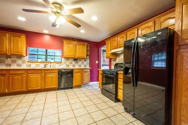 kitchen with black appliances, tasteful backsplash, under cabinet range hood, and light countertops