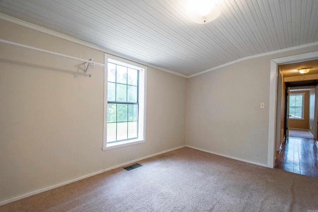 carpeted empty room with baseboards, visible vents, and ornamental molding