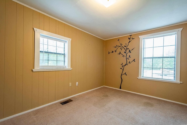 carpeted spare room with ornamental molding, visible vents, and baseboards