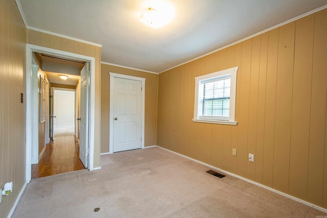 unfurnished bedroom with carpet floors, visible vents, crown molding, and baseboards