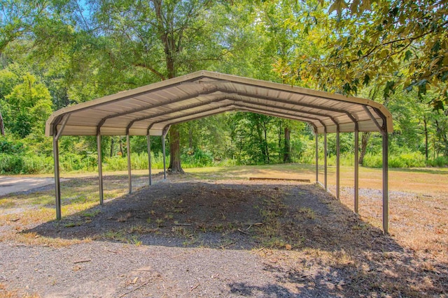 view of parking with a wooded view and a carport