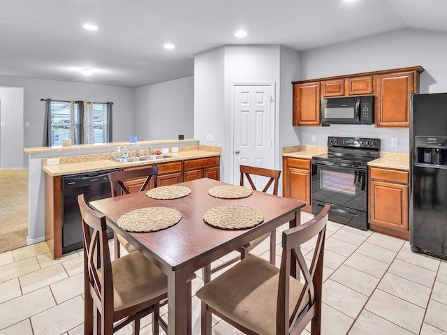 kitchen featuring brown cabinets, light countertops, a sink, and black appliances