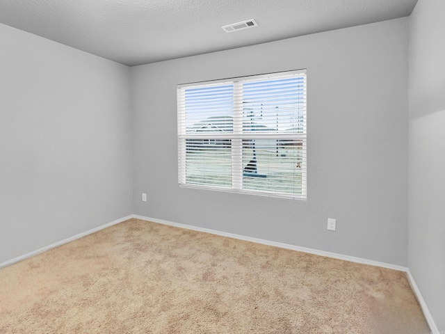 unfurnished room with baseboards, a textured ceiling, visible vents, and carpet flooring