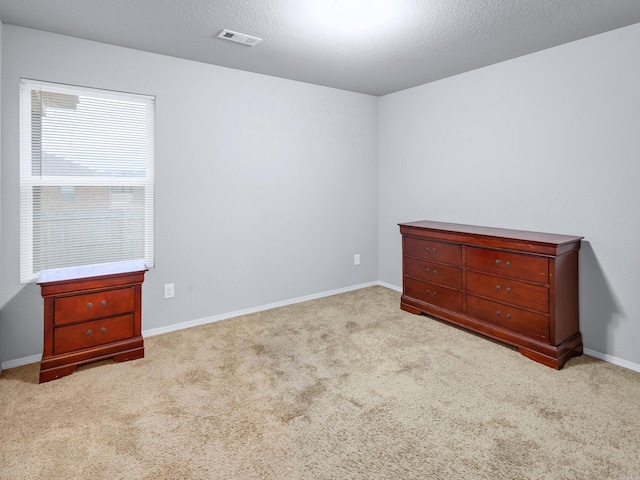 unfurnished bedroom featuring carpet, visible vents, and a textured ceiling