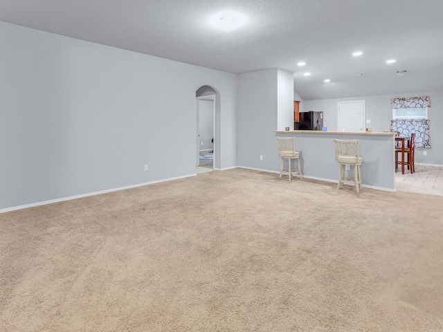 unfurnished living room with light carpet, baseboards, arched walkways, and recessed lighting