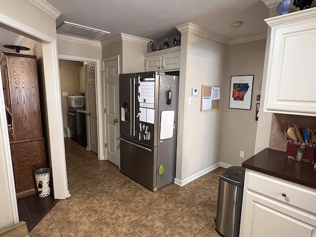 kitchen with dark countertops, stainless steel fridge, white cabinetry, and crown molding