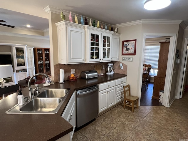 kitchen featuring dark countertops, stainless steel dishwasher, white cabinetry, a sink, and tile patterned floors