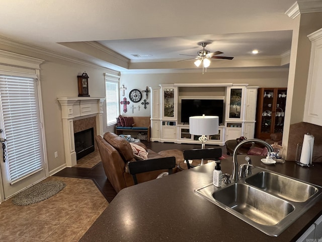 kitchen featuring crown molding, a premium fireplace, a raised ceiling, and a sink