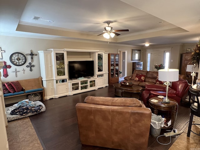 living area with ornamental molding, a tray ceiling, visible vents, and a ceiling fan