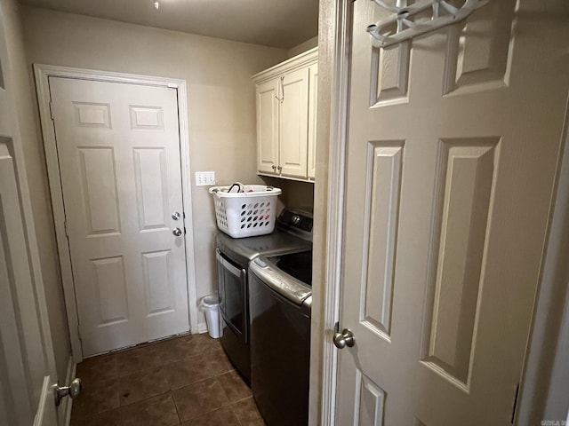 laundry area featuring dark tile patterned flooring, cabinet space, and washer and clothes dryer