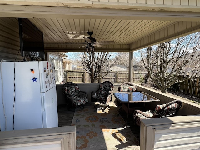 view of patio / terrace with a carport, fence, and ceiling fan