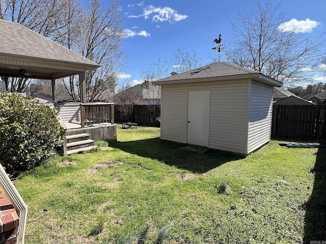 view of yard featuring an outdoor structure, fence, a ceiling fan, a wooden deck, and a shed