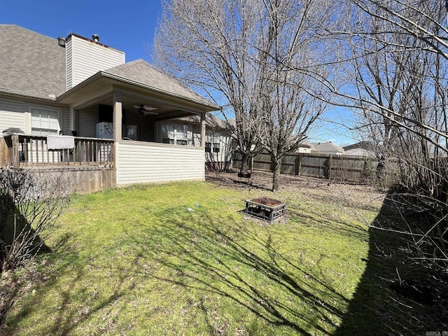 view of yard featuring a ceiling fan, fence, and a fire pit