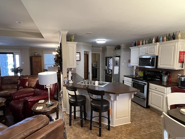 kitchen with open floor plan, appliances with stainless steel finishes, dark countertops, and a sink