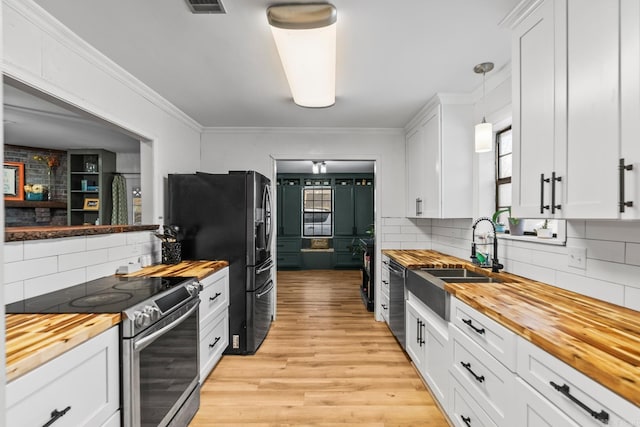 kitchen featuring wooden counters, appliances with stainless steel finishes, a sink, and light wood-style flooring