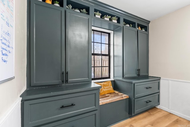 mudroom with light wood-type flooring, wainscoting, and a decorative wall