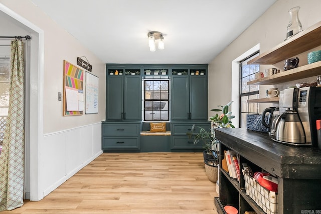 mudroom featuring light wood-style floors, a decorative wall, and a wainscoted wall