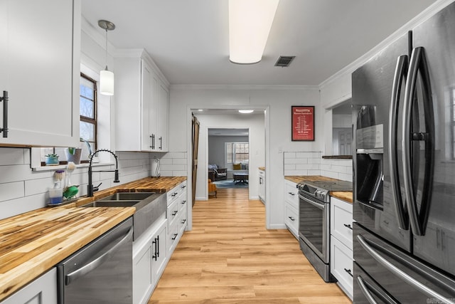 kitchen with butcher block countertops, a sink, visible vents, light wood-style floors, and appliances with stainless steel finishes