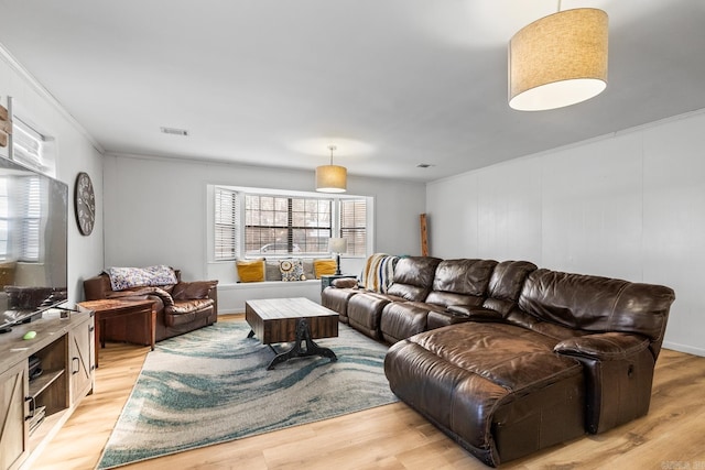 living area with crown molding, visible vents, and light wood-style floors