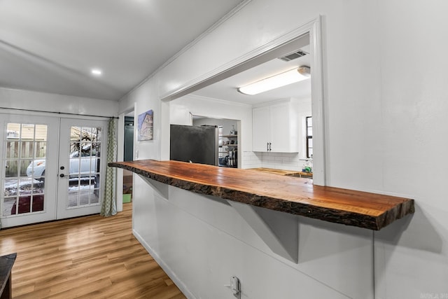 bar featuring french doors, tasteful backsplash, visible vents, freestanding refrigerator, and light wood-type flooring