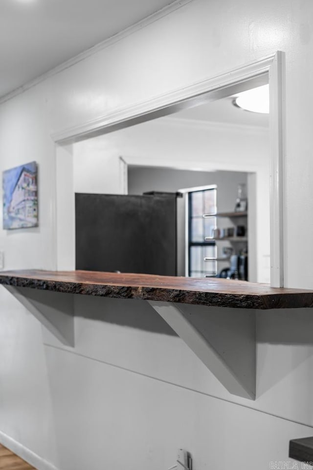 room details featuring baseboards, crown molding, and freestanding refrigerator